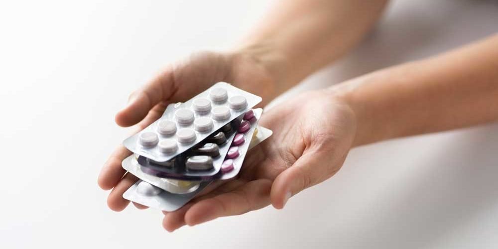 Arzneimittel_Hand_Low-1000×500.jpg Hände halten mehrere Blisterverpackungen mit unterschiedlichen Tabletten in verschiedenen Farben.