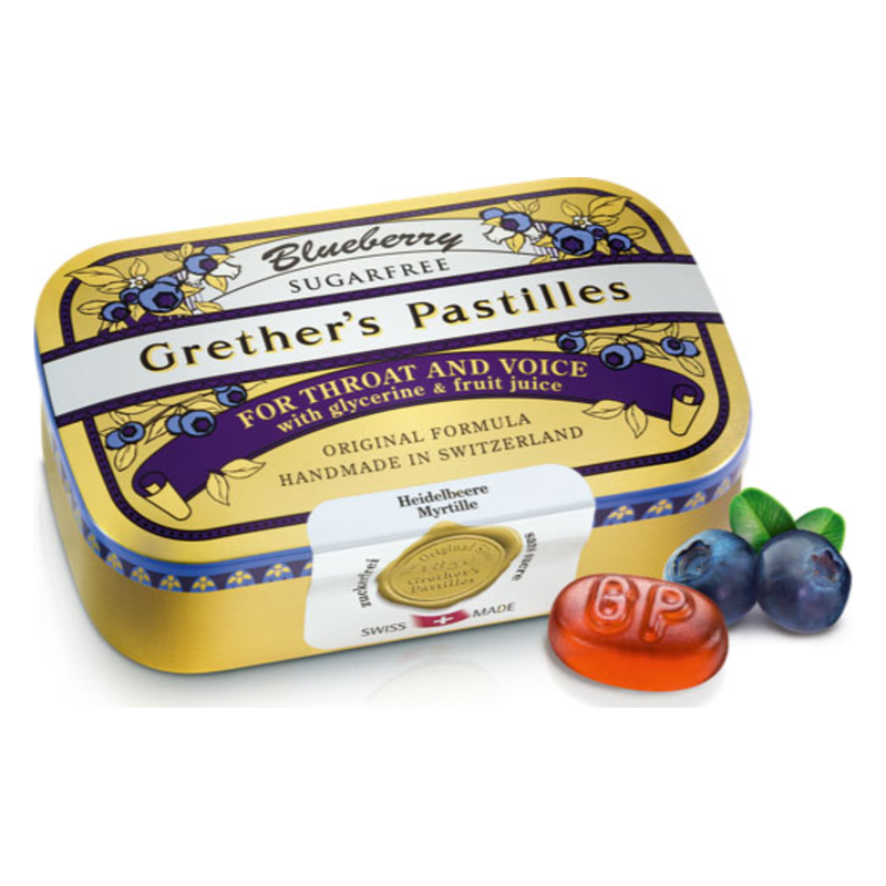 Blaubeer-Vollkonservierte Grether's Pastillen in einer gelben Dose, mit einer roten Pastille und frischen Heidelbeeren daneben.