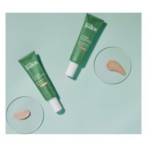 Zwei grüne Tuben der Gesichtspflege von Dr. Babor stehen neben Produkten auf einem runden Glasplättchen.