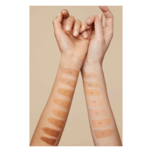 Zwei Hände mit Farbtests für Makeup-Töne auf den Unterarmen, nummeriert von 01 bis 15 auf einer neutralen Hintergrundfarbe.