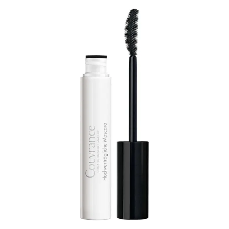 Eine Packung Mascara mit weißem Körper und schwarzem Deckel, daneben eine Bürste mit feinen Borsten.